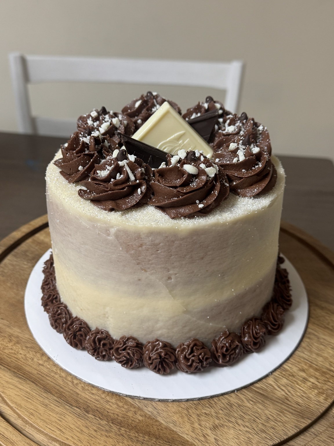 Finished white chocolate mocha customer cake with chocolate rosettes and white and dark chocolate pieces